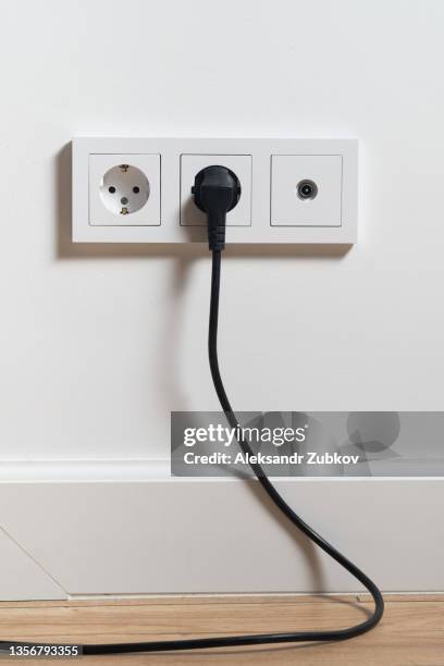 electrical outlet, cable and electrical plug on a white wall background. the concept of technology. a copy of the space for text and labels. - presa di corrente foto e immagini stock