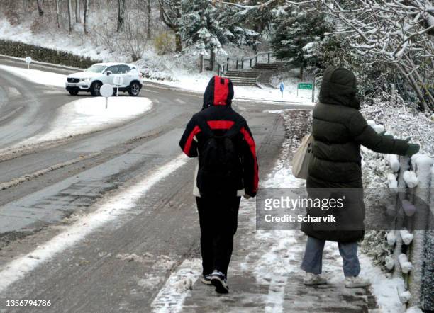 two young people walking at sidewalk covered with thaw snow. - melting snowball stock pictures, royalty-free photos & images