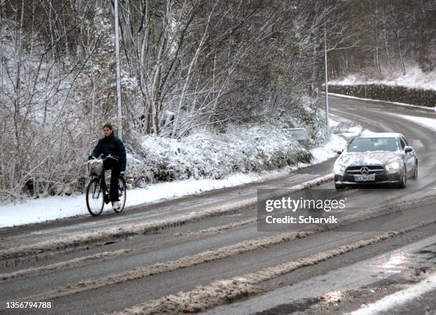 young woman cycling in slippery thaw snow  on bicycle lane. - snow melting on car stock pictures, royalty-free photos & images