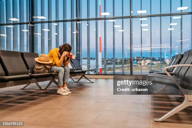 tired woman waiting her delayed flight on airport - travel cancellation stock pictures, royalty-free photos & images