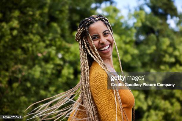 joven risueña girando su largo cabello trenzado afuera en verano - trenzado fotografías e imágenes de stock