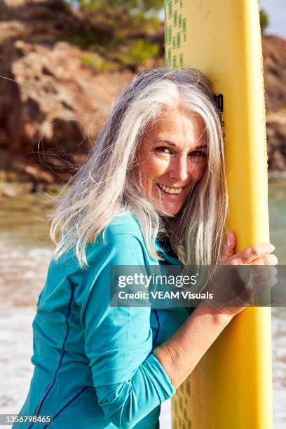 mature woman on the beach with a surfboard - older woman bathing suit stock pictures, royalty-free photos & images