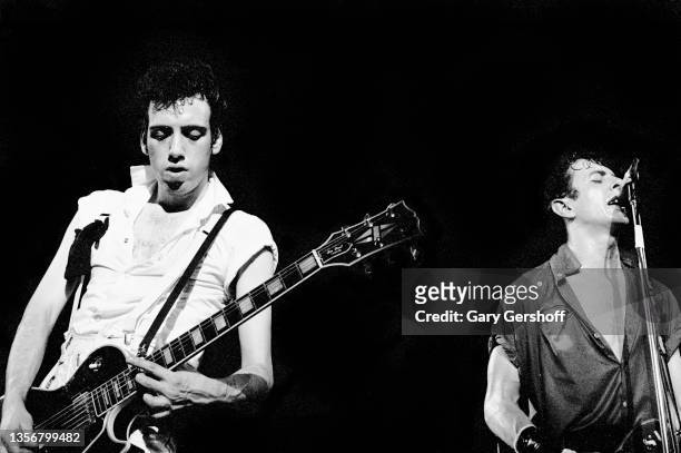 British Punk musicians Mick Jones and Joe Strummer , both of the group the Clash, play guitars as they perform onstage at the Capitol Theatre,...