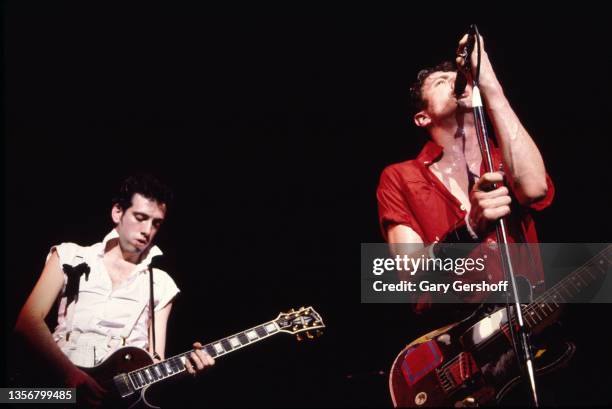 British Punk musicians Mick Jones and Joe Strummer , both of the group the Clash, play guitars as they perform onstage at the Capitol Theatre,...