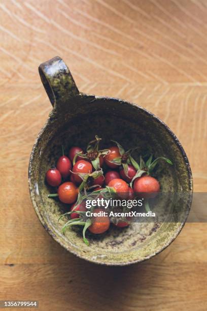 view of wild rose hips, on wooden table - rose hip stock pictures, royalty-free photos & images