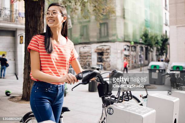 young asian female tourist renting an e-bike to explore madrid - madrid travel stock pictures, royalty-free photos & images