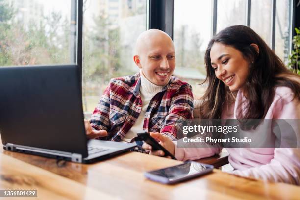 glückliches paar sitzt im café mit laptop und surfen im internet - cellphone cancer illness stock-fotos und bilder