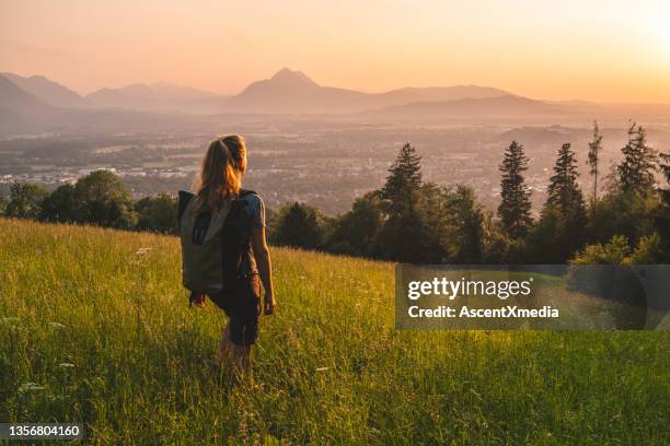 female hiker relaxes on grassy mountain ridge - discovery bags walking stockfoto's en -beelden