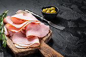 Pork ham slices on cutting board, Italian Prosciutto cotto. Black background. Top view. Copy space