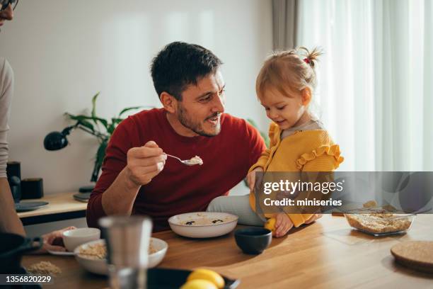 padre alimentando a una hija pequeña - baby feeding fotografías e imágenes de stock