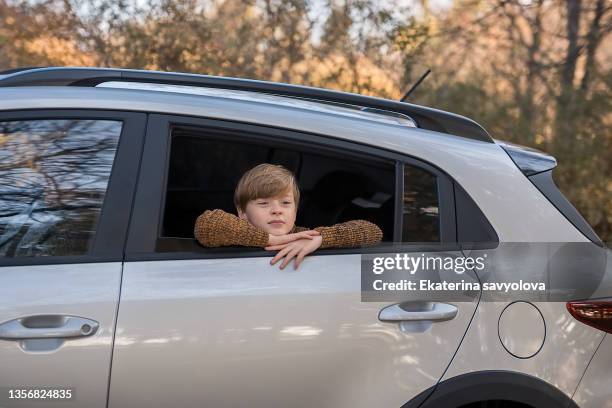 a happy boy looks out of the car window. the concept of holidays, recreation, travel. - car boot stock pictures, royalty-free photos & images