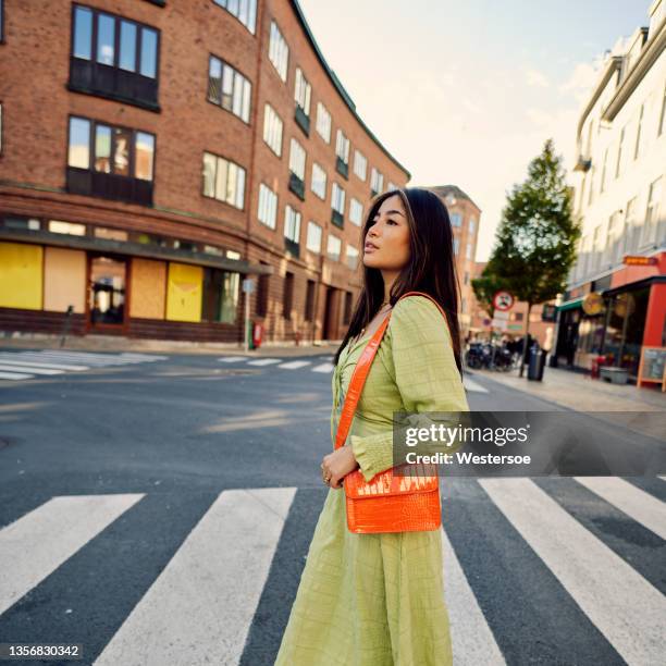 joven asiática cruzando la carretera - bolso naranja fotografías e imágenes de stock
