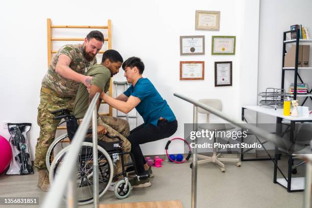 young military soldier uses parallel bars in a rehab center. - american indian military stock pictures, royalty-free photos & images