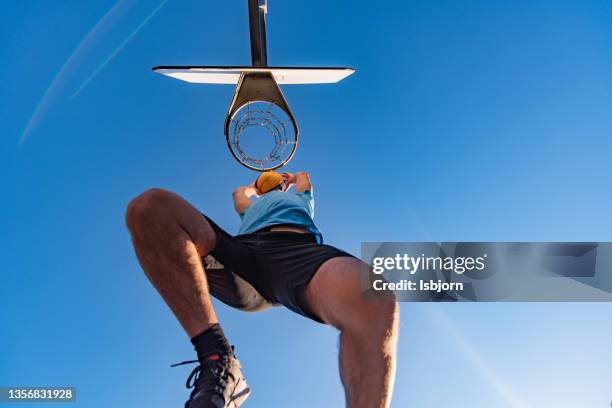 below view of basketball player placing ball in the hoop - man looking up imagens e fotografias de stock