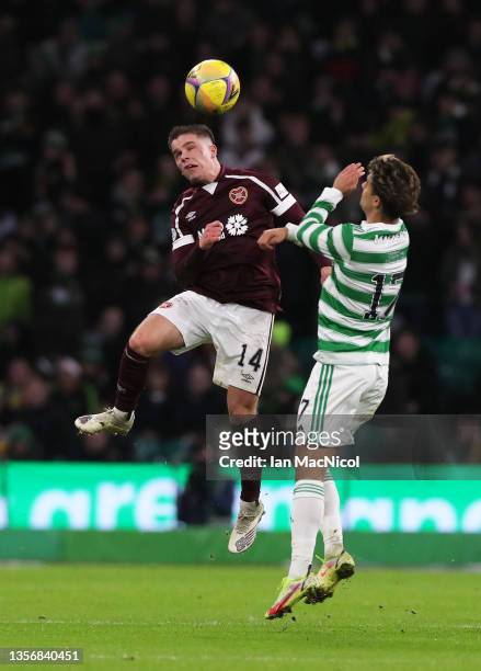 Cameron Devlin of Heart of Midlothian competes for a header with Jota of Celtic during the Cinch Scottish Premiership match between Celtic FC and...