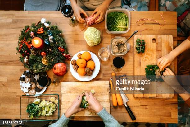 females making christmas meal at decorated kitchen table - rollende keukens stockfoto's en -beelden