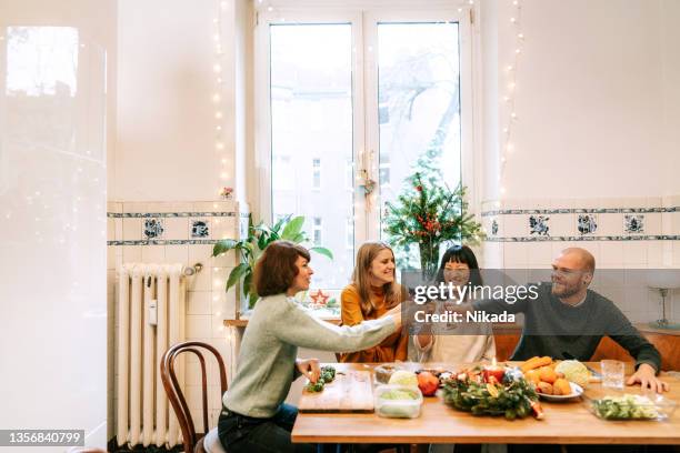multirassische freunde klirren weingläser, während sie zu hause weihnachtsessen kochen - kochen freunde stock-fotos und bilder