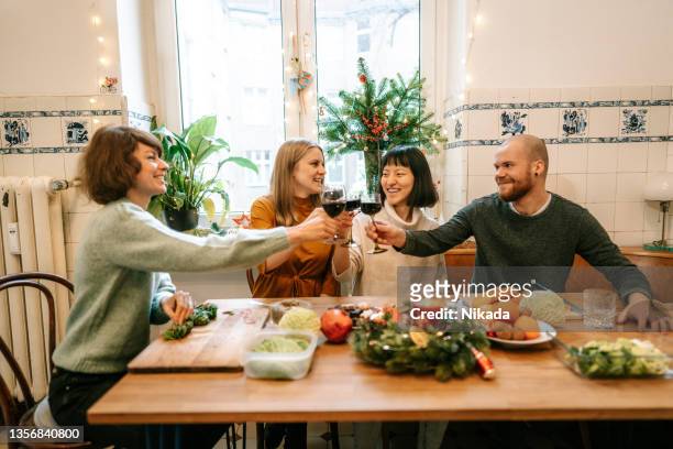 Friends having red wine while making christmas meal at home