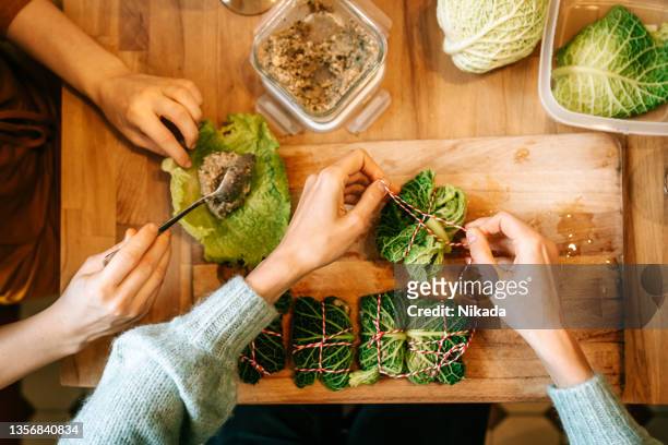 females making stuffed christmas cabbage rolls on kitchen table - cabbage roll stock pictures, royalty-free photos & images