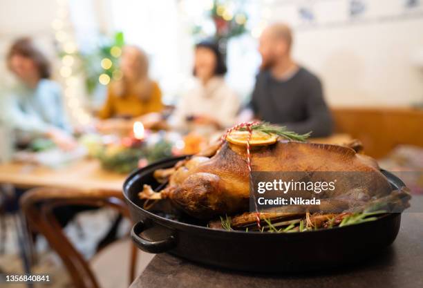 roasted goose for thanksgiving with friends at dining table - goose meat stock pictures, royalty-free photos & images