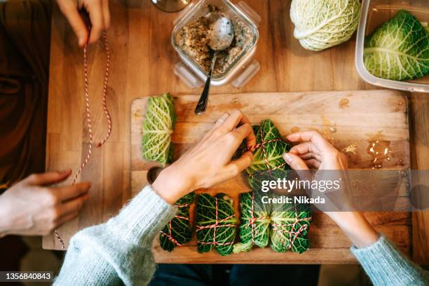 women making vegetarian savoy cabbage rolls for christmas dinner - vegetarian christmas dinner stock pictures, royalty-free photos & images