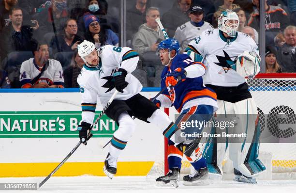 Erik Karlsson of the San Jose Sharks is checked by Cal Clutterbuck of the New York Islanders during the first period at the UBS Arena on December 02,...