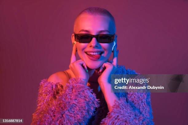 portrait of a cheerful dancing woman listening to music through a device headphones - modern dancing stockfoto's en -beelden