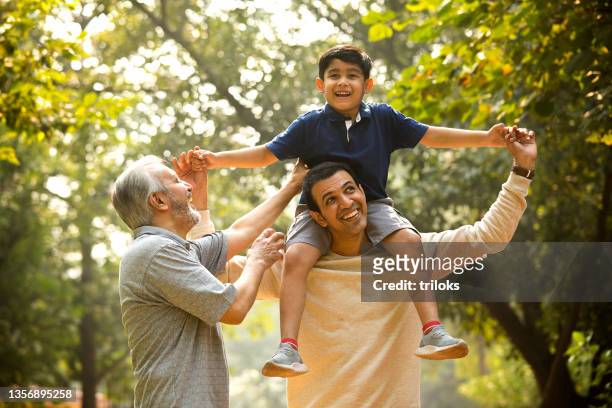 famiglia di tre generazioni che si diverte al parco - asian and indian ethnicities foto e immagini stock