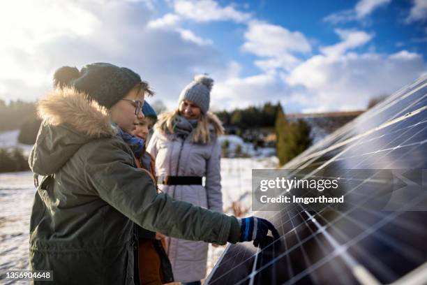 mother explaining solar panels technology to the kids on a winter day. - electric people stockfoto's en -beelden