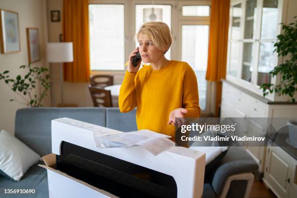 a woman, after receiving her home delivery, rings the company on her mobile - shopping disappointment stock pictures, royalty-free photos & images