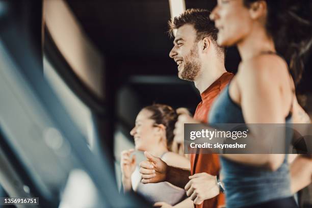 profilansicht eines glücklichen männlichen athleten, der auf dem laufband in einem fitnessstudio voller menschen läuft. - happy male side view stock-fotos und bilder