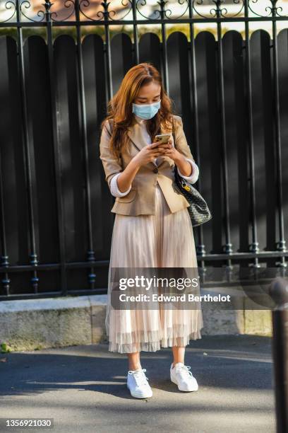 Guest wears a beige ribbed high neck pullover, a beige blazer jacket, a beige tulle accordion / pleated midi skirt, a black and gray print pattern...