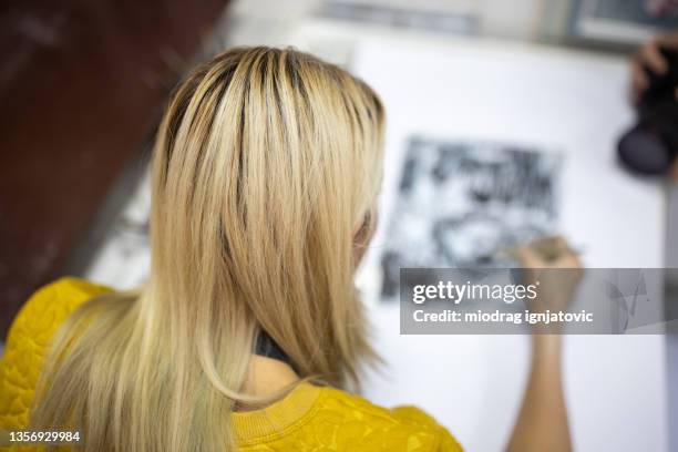 rear-view of female artist painting with ink on paper - table font view stock pictures, royalty-free photos & images