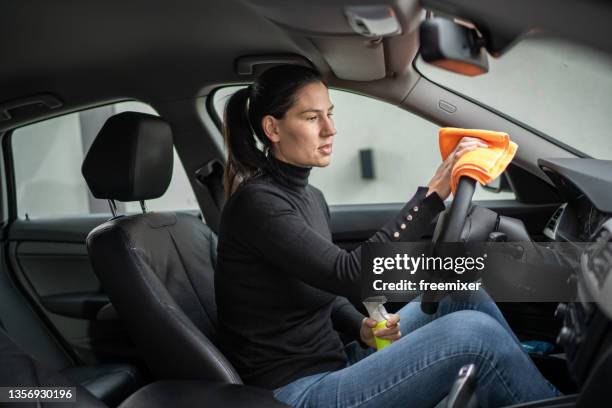 woman sitting in car and cleaning steering wheel with rag - cleaning inside of car stock pictures, royalty-free photos & images