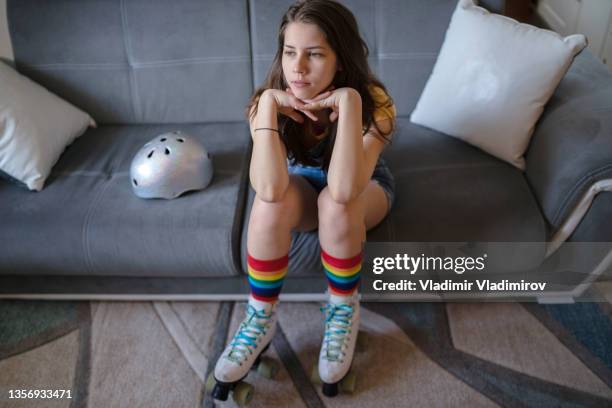 a bored teenager wearing roller skates sitting on a sofa - teenager cycling helmet stock pictures, royalty-free photos & images