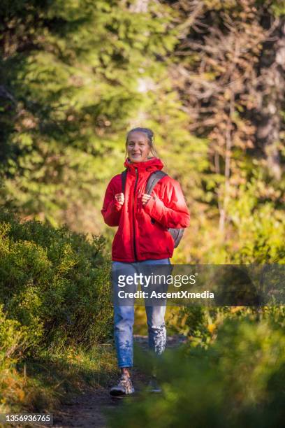 female hiker follows trail through forest - red jacket stock pictures, royalty-free photos & images