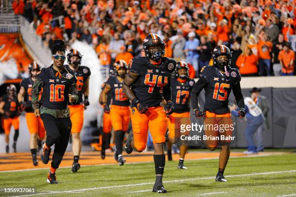Linebacker Kamryn Farrar and safety Ty Williams of the Oklahoma State Cowboys run onto the field for a game against the Oklahoma Sooners at Boone...