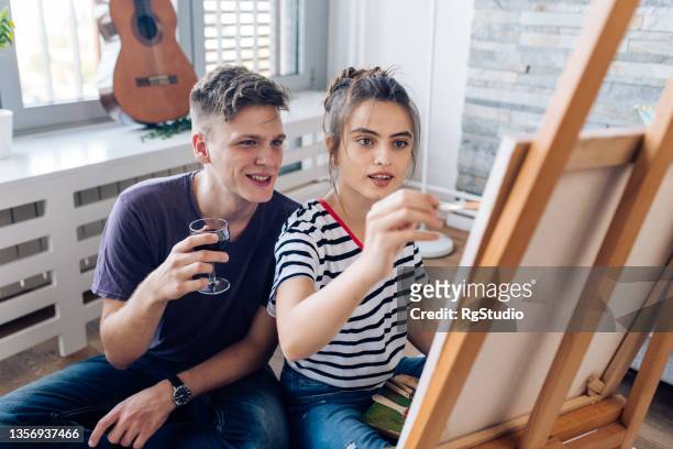 girl painting and enjoying with her boyfriend while he's drinking wine - house for an art lover stock pictures, royalty-free photos & images