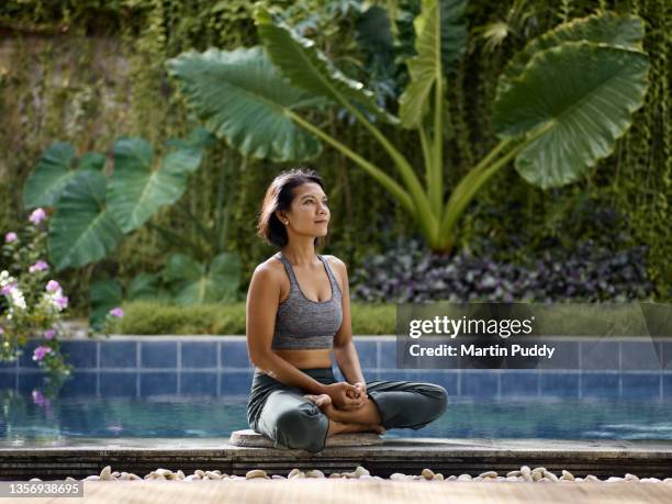 asian woman practicing yoga during home workout, in front of pool garden - daily life in indonesia stock pictures, royalty-free photos & images