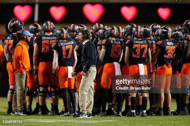 Head coach Mike Gundy of the Oklahoma State Cowboys huddles with his team during a game against the Oklahoma Sooners in the fourth quarter at Boone...