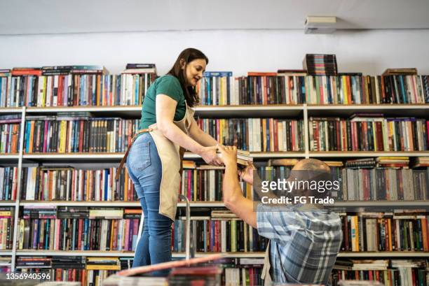 trabajadores de la librería organizando libros en el estante - libreria fotografías e imágenes de stock