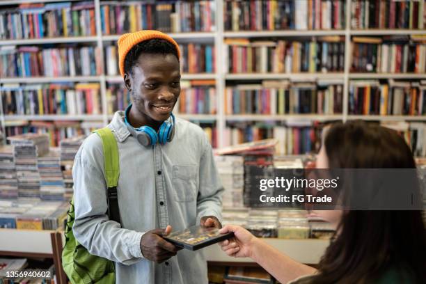 happy young man buying something in a thrift store - dvd stock pictures, royalty-free photos & images