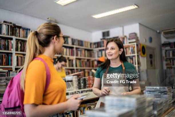 saleswoman helping customer in a thrift store - book store stock pictures, royalty-free photos & images