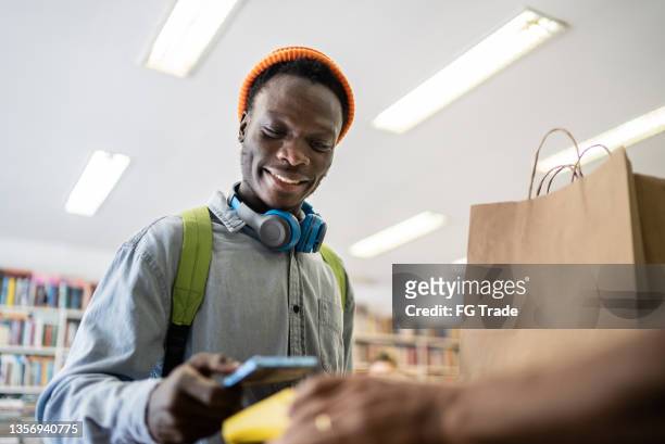 young man paying in a thrift store - book barcode stock pictures, royalty-free photos & images