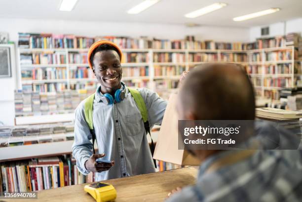 young man paying in a thrift store - point of sale stock pictures, royalty-free photos & images