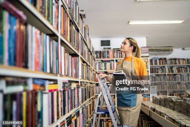 bookseller arranging books in a shelf - book-store-staff stock pictures, royalty-free photos & images