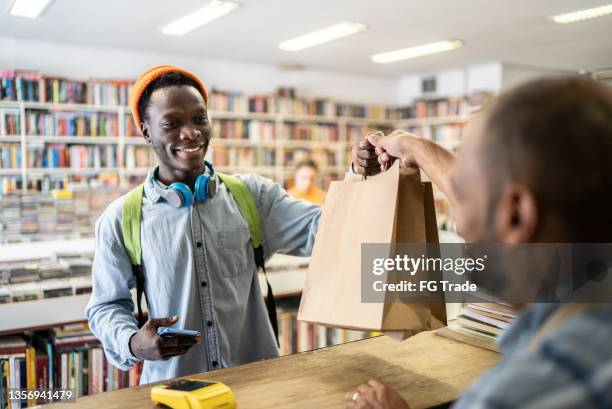 young man paying in a thrift store - book barcode stock pictures, royalty-free photos & images