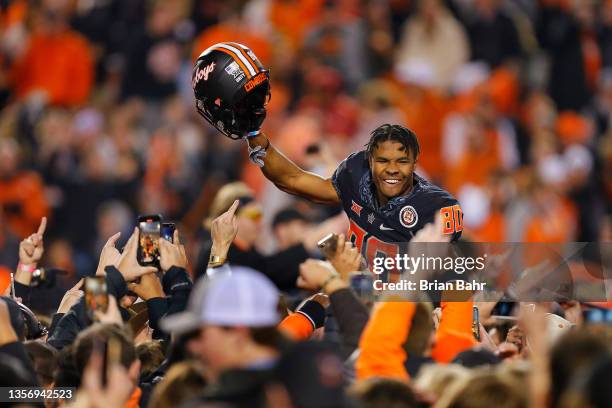 Wide receiver Brennan Presley of the Oklahoma State Cowboys celebrates a win over the Oklahoma Sooners atop the shoulders of students as fans rush...