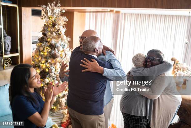 famiglia che abbraccia e ragazza adolescente che applaude durante il natale a casa - take care foto e immagini stock