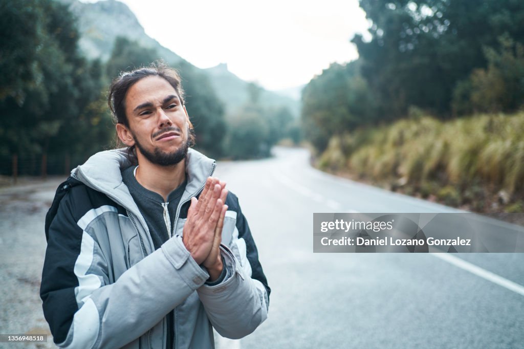 Funny traveler hitchhiking on road in mountains